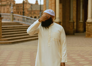 Man in een crèmekleurige qamis met witte kufi op de Plaza de España in Sevilla