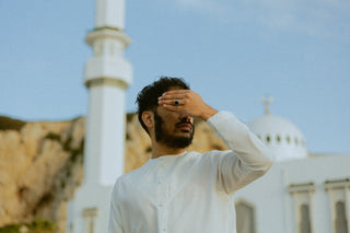 Man in een witte qamis voor de minaret van de moskee bij Europa Point in Gibraltar