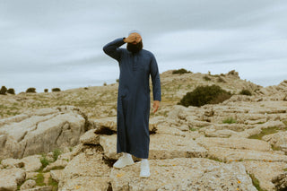 Man in een navy qamis met witte kufi in het rotslandschap van El Torcal